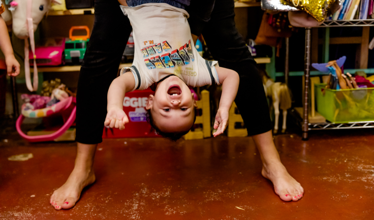 Parent holding an excited toddler upside down in the air