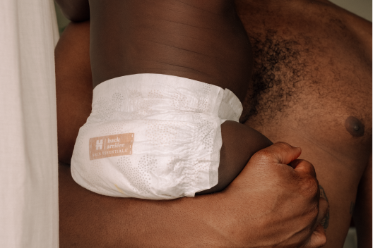 Baby wearing Huggies® Skin Essentials™ diaper while being held